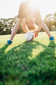 Boy on soccer field, bending over, looking through his legs