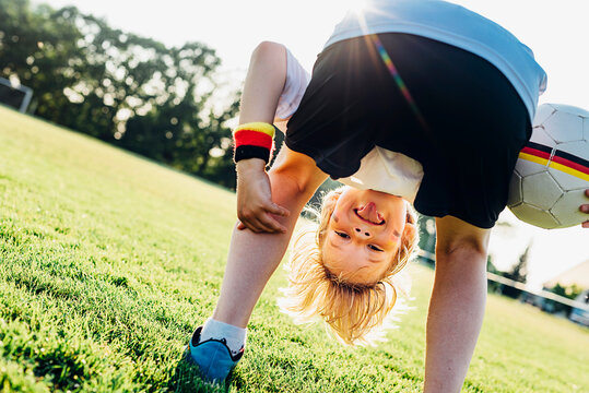 Boy on soccer field, bending over, looking through his legs