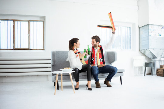 Happy German football fan couple sitting on couch