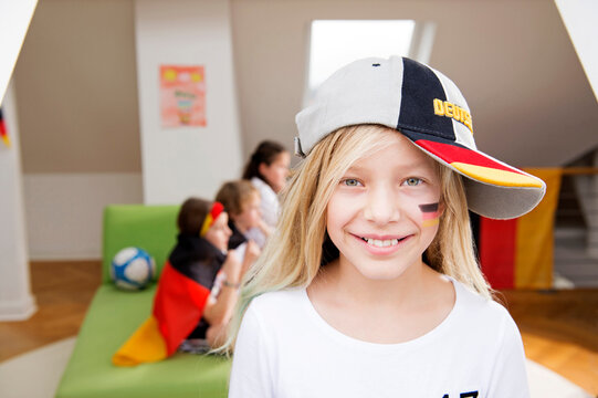 Portrait of a girl with German face paint and cap with friends in background