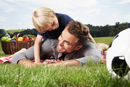 Germany, Cologne, Father and son playing around on picnic blanket
