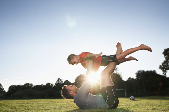 Germany, Cologne, Father holding son aloft on soccer field