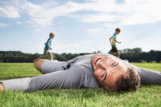 Germany, Cologne, Father and sons playing soccer