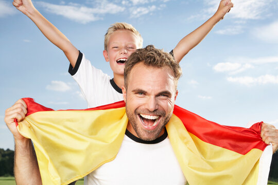 Germany, Cologne, Father and son cheering in football outfit