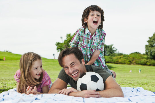 A joyful Bavarian family spending a leisurely day in the park, basking in the sun on a cozy picnic blanket