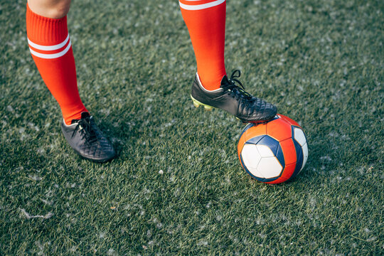 Legs of a woman standing on football ground with the ball