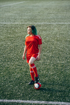 Young woman standing on football ground with the ball