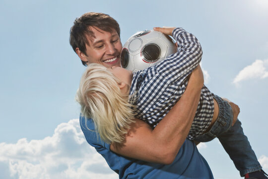Germany, Cologne, Father and son (2-3 Years) playing with ball, smiling