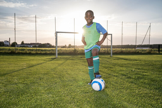 Portrait of confident young football player with ball on football ground