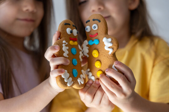 Sisters Sharing Sweet Holiday Moments. Two Young Sisters Smiling With Colorful Gingerbread Cookies And Bright Icing