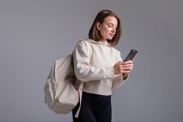 Naklejka premium young woman holds a smartphone and a laptop in her hands on a light background in a studio, space for text, mok up