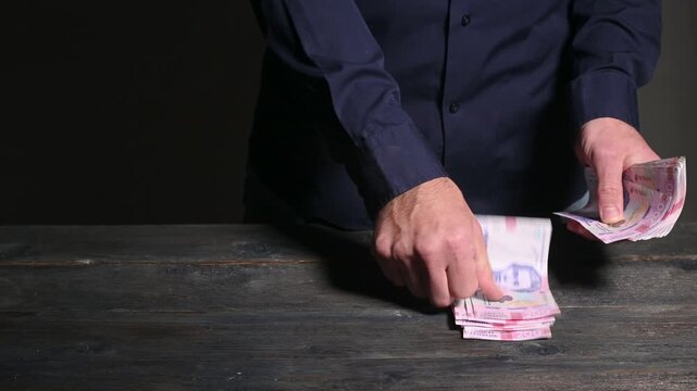 Person places Ukrainian hryvnia bills in neat rows showing accounting and cash organization. Hands sort banknotes in denominations of 200 hryvnias business order, finance, and money management.