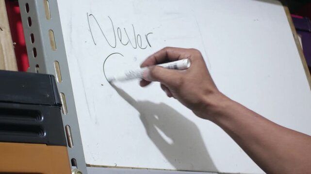 close up of hand writing never give up on white board