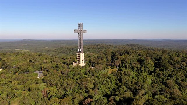 A towering cross stands amidst dense forest in Parque Tem&aacute;tico de la Cruz, Santa Ana, Argentina. Ideal for travel content or cultural documentaries.