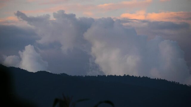 Massive Billowing Clouds Over Mountain Silhouette at Dusk with Airplane Flying By