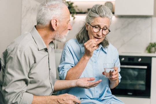 Senior couple, man and woman take pill at home together
