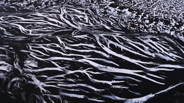 Aerial View of a Braided River System in Iceland with Snow-Covered Banks, Stunning Natural Patterns
