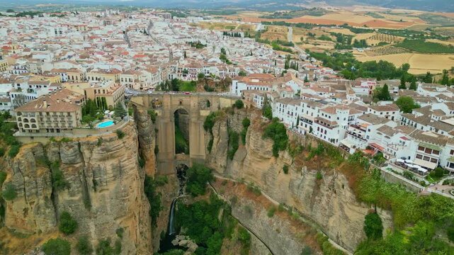 Spectacular view of the historic Puente Nuevo stone bridge in Ronda, Andalusia. Iconic medieval architecture spanning across the deep El Tajo gorge with whitewashed cliffside houses in Spain.