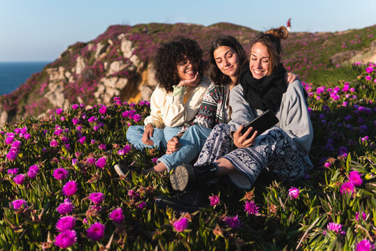 Female friends sitting on Carpobrotus Edulis flower field