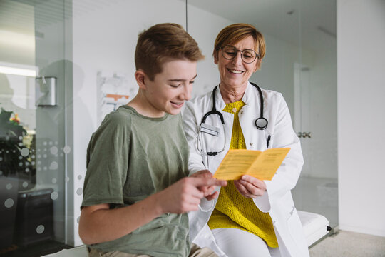 Doctor explaining vaccination to teenage boy in medical practice