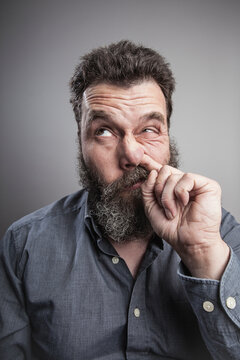 Portait of a mature man with full beard, picking his nose
