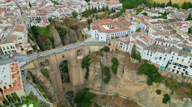 Spectacular view of the historic Puente Nuevo stone bridge in Ronda, Andalusia. Iconic medieval architecture spanning across the deep El Tajo gorge with whitewashed cliffside houses in Spain.
