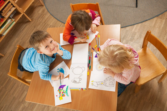 Germany, Children in nursery sitting at table drawing pictures, elevated view