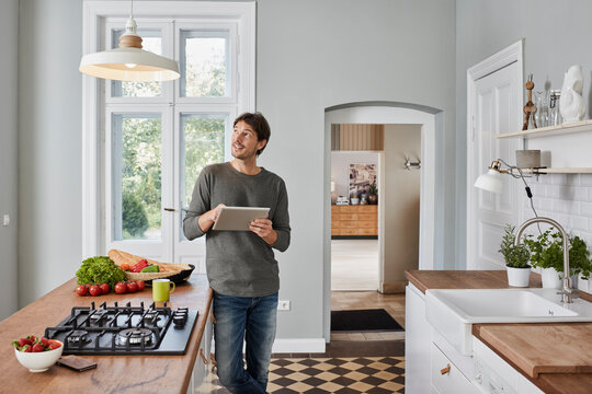 Man using tablet in kitchen looking at ceiling lamp