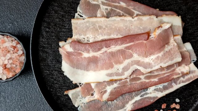Raw fresh bacon slices with layers of meat or prosciutto with salt and spices. Raw bacon as a food background for your design
