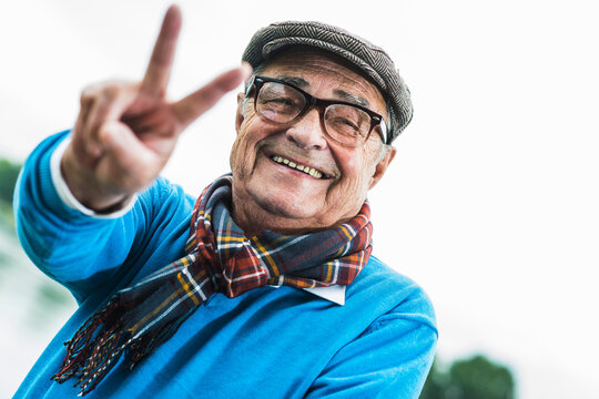 Portrait of happy senior man showing victory sign