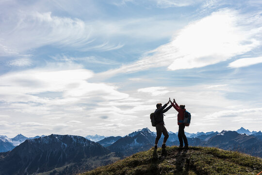 Austria, Tyrol, young couple standing in mountainscape cheering