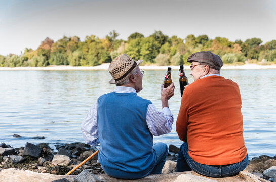 Old friends sitting by the riverside, drinking beer