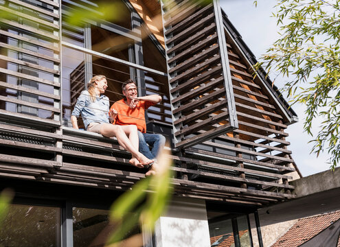 Mature couple relaxing together on balcony of their house