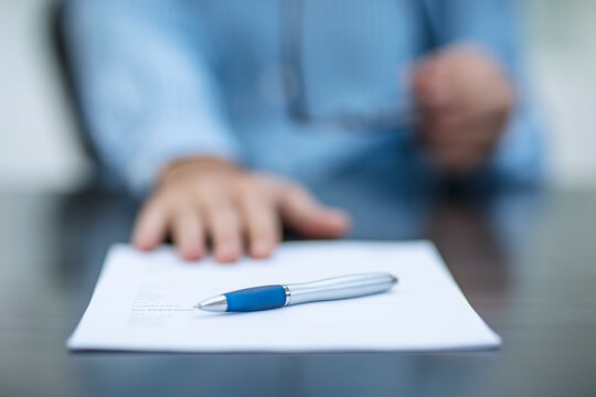 Person sitting at office desk with documents and a pen