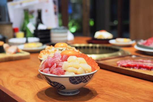 Bowl of sliced raw fresh tuna, hotate or scallop, salmon and salmon roe served with pickled ginger and wasabi topped with marinated egg yolk over steamed rice.