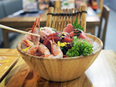 A bowl of fresh sliced tuna sushi; honmaguro otoro, chutoro, akami and shrimp served with wasabi and seaweed over ice.