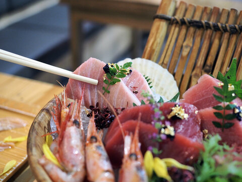 A bowl of fresh sliced tuna sushi; honmaguro otoro, chutoro, akami and shrimp served with wasabi and seaweed over ice.