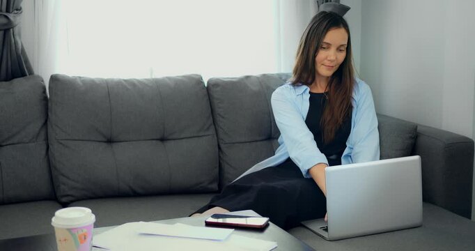 Woman examines financial records. Individual analyzes budget papers meticulously at home. Woman focusfully reviews and organizes financial documents and expense receipts in tidy home office