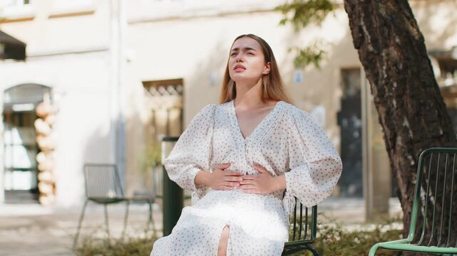 Caucasian young woman traveler feeling sudden strong abdominal stomach ache gastritis problem. Upset tourist lady having symptom poisoning diarrhea indigestion peptic ulcer pancreatitis on city street