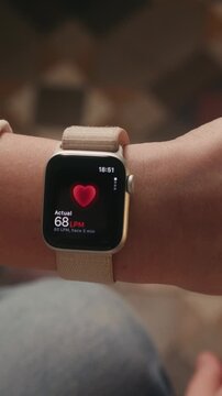 Vertical footage, close-up of female hand using smartwatch to measure heart rate, health monitoring concept. High quality 4k footage