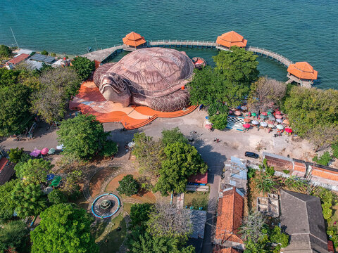 Aerial view of the giant turtle-shaped building at Kura-Kura Ocean Park with coastal walkways and pavilions by the sea in Jepara, Central Java, Indonesia.