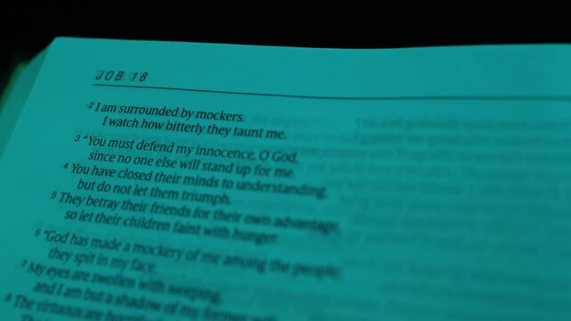 Macro close-up shot of open Bible pages from the Book of Job, lit with moody blue lighting, showing sharp text detail and angled paper texture for a contemplative, dramatic look.