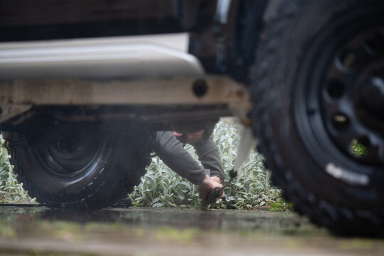 Man washing off-road vehicle undercarriage with pressure washer