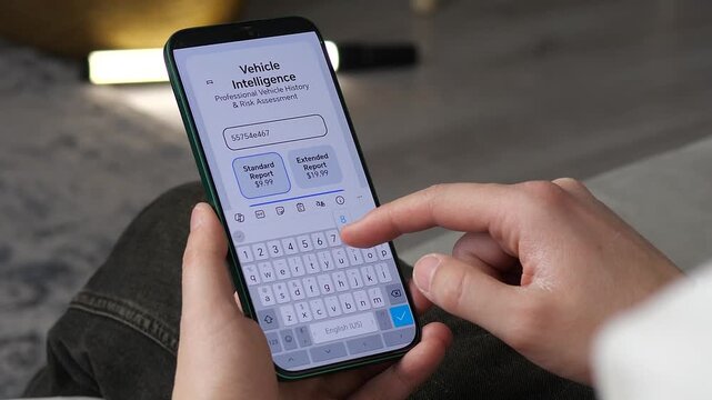 Close-up of a person typing a VIN into a vehicle history app on a smartphone. Features professional risk assessment UI. Perfect for automotive services, used car buying guides, and insurance marketing