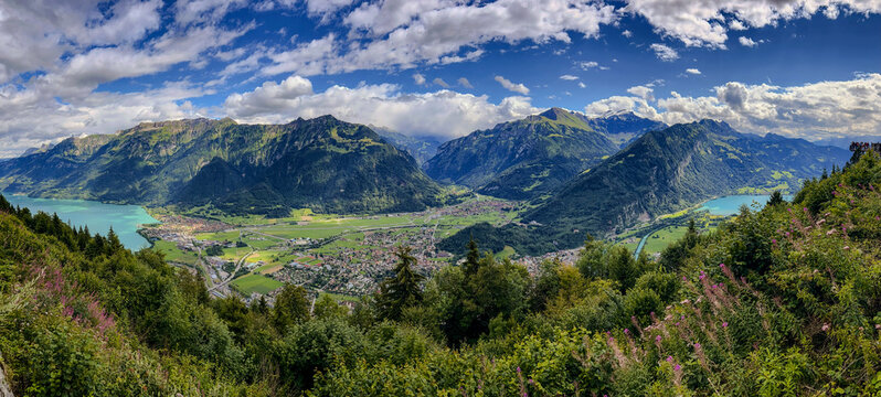 Aerial view of the town of Interlaken nestled between Lake Brienz and Lake Thun, surrounded by the majestic Swiss Alps under a dramatic cloudy sky Interlaken, Canton of Bern, Switzerland.