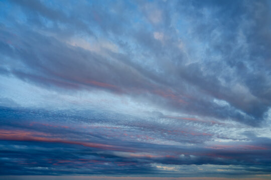 The sky displays a beautiful mix of blue and gray clouds, with horizontal streaks of pink and orange light spreading across the horizon during sunset
