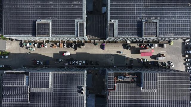 Aerial view of rooftop solar panel arrays and parking lot with cars in modern city