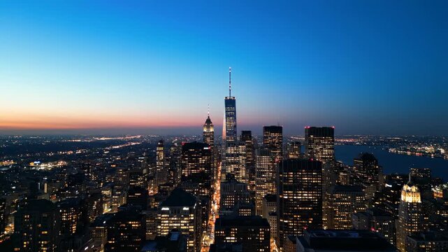 Majestic cityscape at twilight unfolds with towering illuminated skyscrapers piercing the darkening sky, offering a breathtaking panorama of urban sprawl and distant twinkling lights