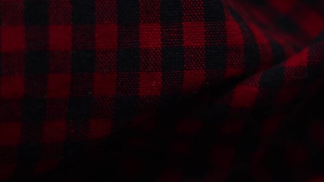 Red and black plaid flannel fabric texture moving in dark background