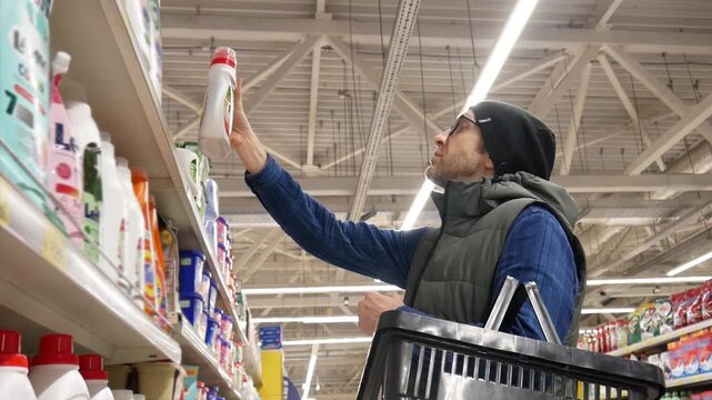 A male customer with a shopping basket chooses fabric softener